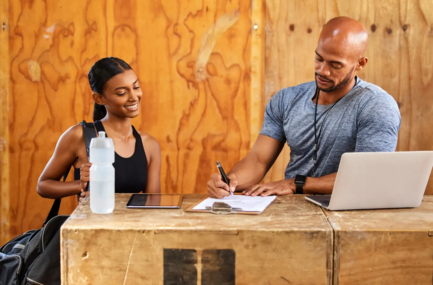 Shot of a young man and woman reading over a document in a gym