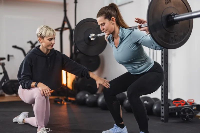 A coach correcting a client’s squat technique